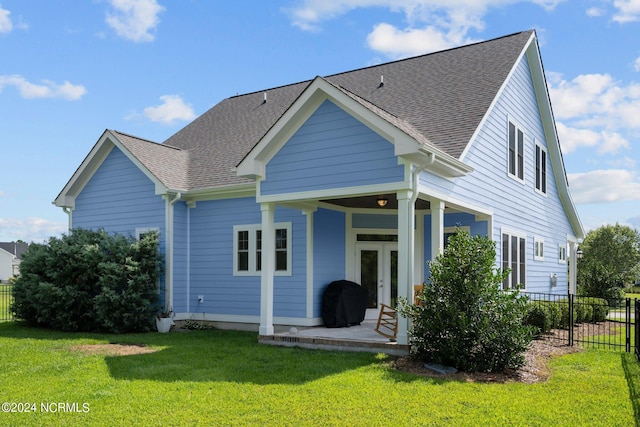 back of property featuring french doors, fence, roof with shingles, and a lawn