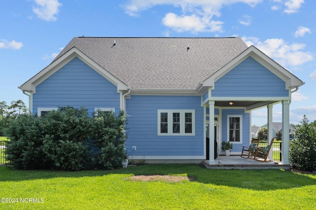 back of house with a lawn and roof with shingles