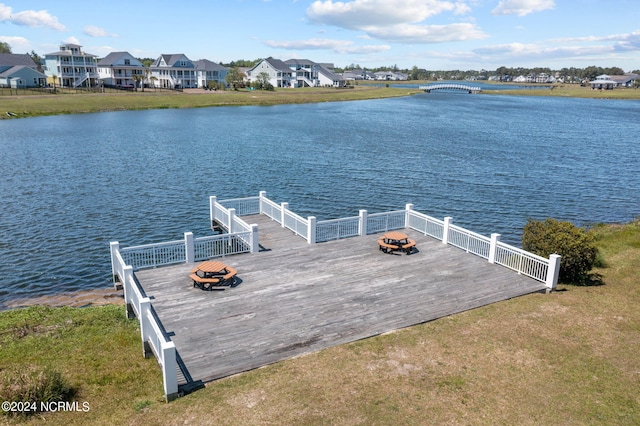 view of dock featuring a residential view, a yard, and a water view