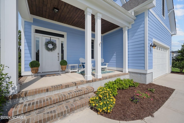 view of exterior entry featuring a porch, concrete driveway, and an attached garage