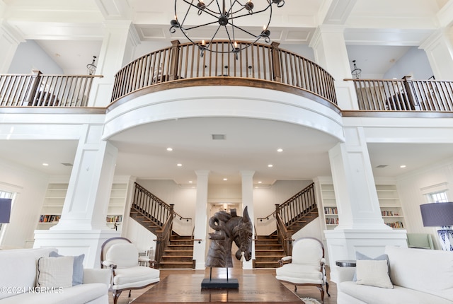 living room with stairs, a high ceiling, built in features, and ornate columns