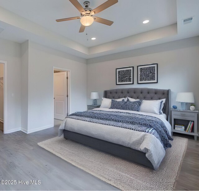 7053 Trailhead Rd, Leland, NC 28451 - bedroom with wood finished floors, baseboards, a raised ceiling, recessed lighting, and a ceiling fan