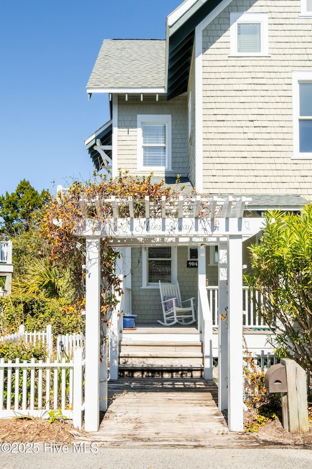 view of front of house featuring a porch, a pergola, and fence