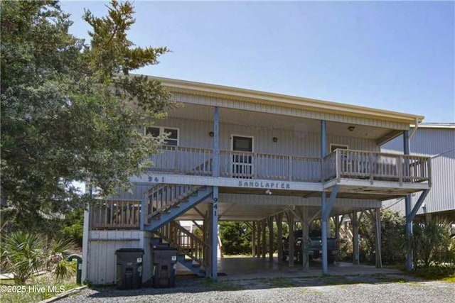 rear view of property with stairway, a carport, and covered porch