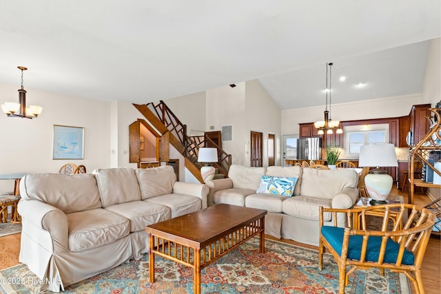 living area featuring lofted ceiling, an inviting chandelier, stairway, and light wood finished floors