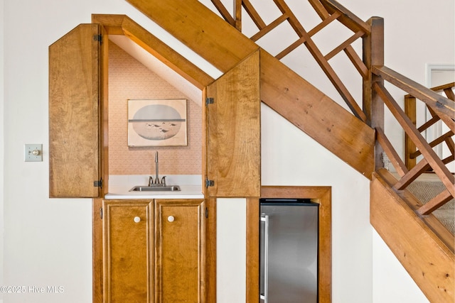 bar featuring lofted ceiling, freestanding refrigerator, a sink, stairs, and indoor wet bar