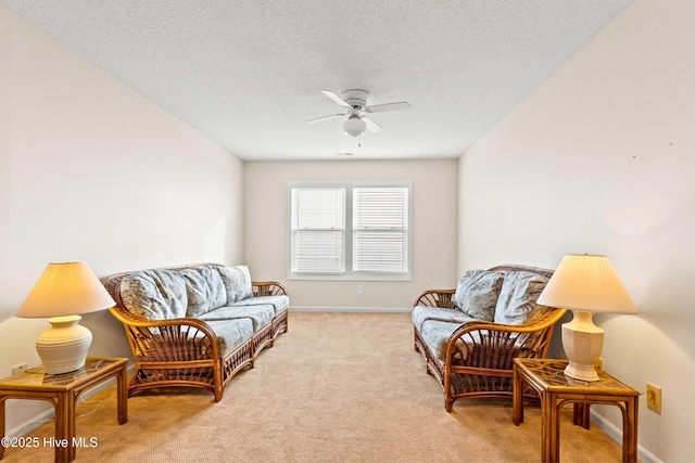 living room with baseboards, light colored carpet, ceiling fan, and a textured ceiling