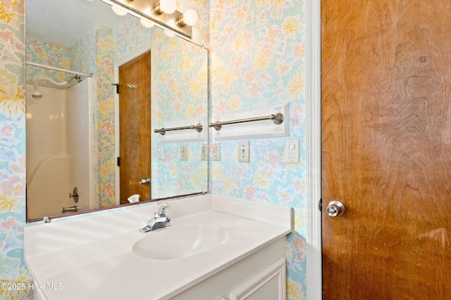 bathroom with wallpapered walls, vanity, and walk in shower