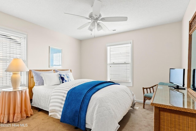 carpeted bedroom with ceiling fan, multiple windows, visible vents, and a textured ceiling