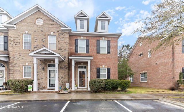 townhome / multi-family property featuring brick siding and uncovered parking