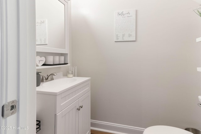 half bath with vanity, toilet, and baseboards