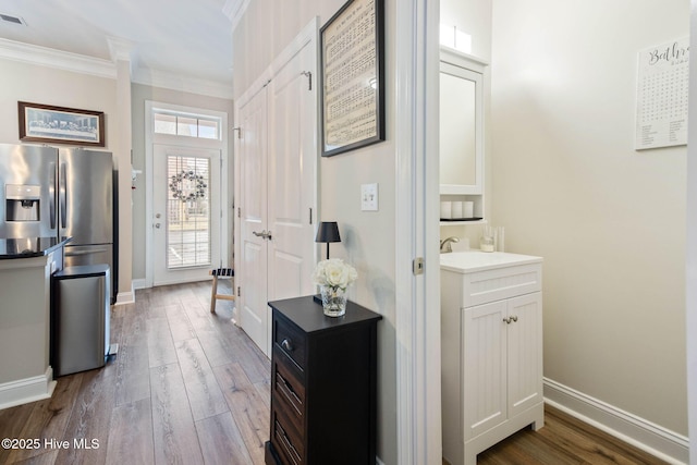 foyer with visible vents, wood finished floors, baseboards, and ornamental molding