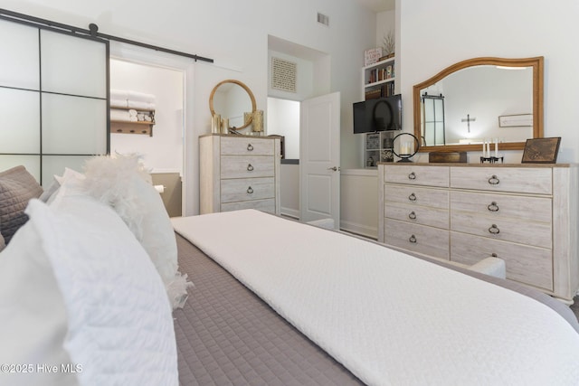 bedroom featuring a barn door, a high ceiling, and visible vents