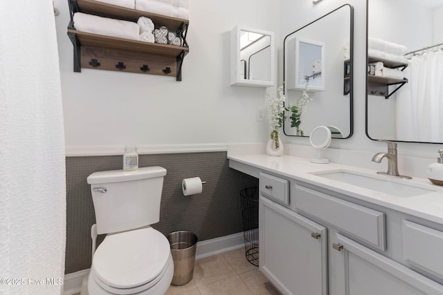 full bathroom featuring tile patterned flooring, toilet, vanity, and wainscoting