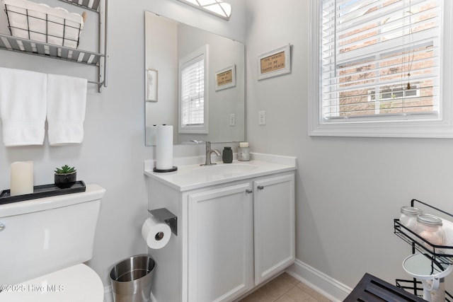 half bathroom featuring tile patterned floors, baseboards, toilet, and vanity