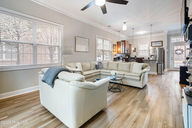 living area featuring light wood-style flooring, baseboards, ornamental molding, and a ceiling fan