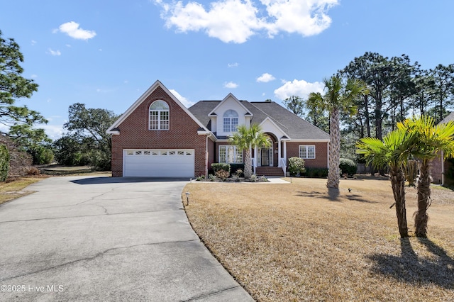 traditional-style home with brick siding, a garage, driveway, and a front yard