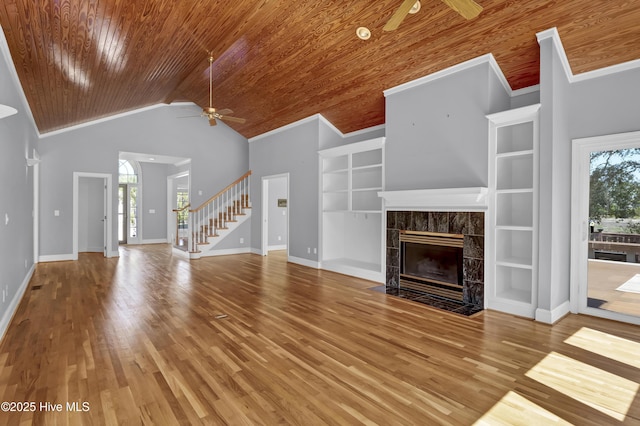 unfurnished living room featuring stairs, a ceiling fan, wood ceiling, and a tile fireplace