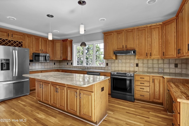 kitchen with a center island, under cabinet range hood, light wood-type flooring, ornamental molding, and appliances with stainless steel finishes