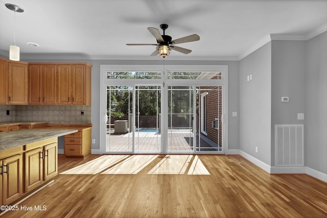 kitchen featuring visible vents, ornamental molding, tasteful backsplash, light wood finished floors, and baseboards