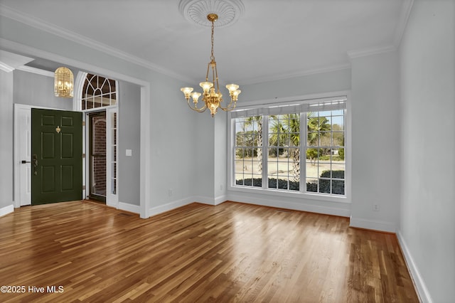 interior space featuring baseboards, an inviting chandelier, wood finished floors, and ornamental molding