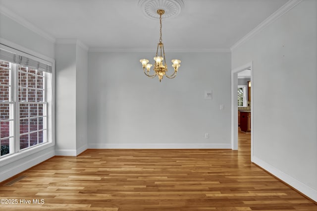 spare room featuring crown molding, light wood-style floors, baseboards, and a chandelier