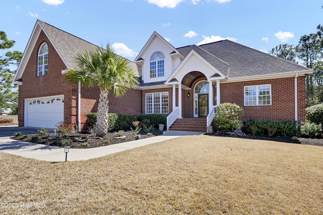 view of front facade with brick siding, a front yard, roof with shingles, driveway, and an attached garage