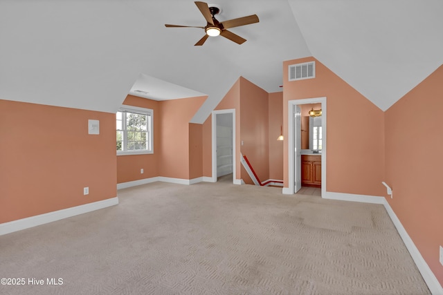 additional living space with visible vents, baseboards, light carpet, and vaulted ceiling