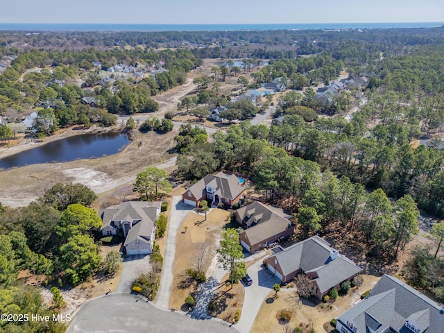 bird's eye view featuring a residential view, a wooded view, and a water view