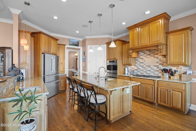 kitchen featuring light stone counters, a kitchen island with sink, appliances with stainless steel finishes, and a sink