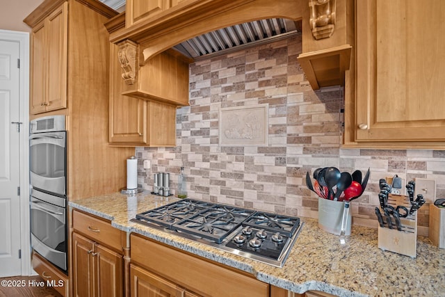 kitchen featuring stainless steel appliances, light stone countertops, tasteful backsplash, and custom range hood