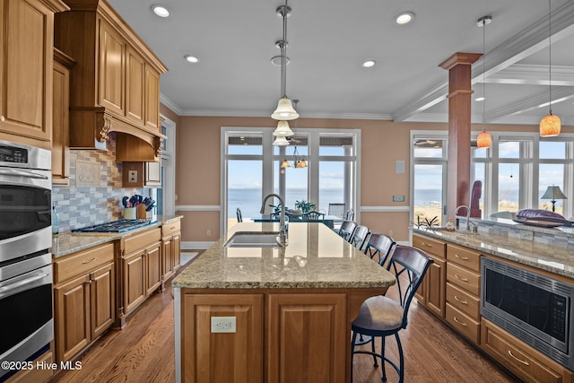 kitchen featuring a sink, stainless steel appliances, dark wood-style floors, and a breakfast bar area