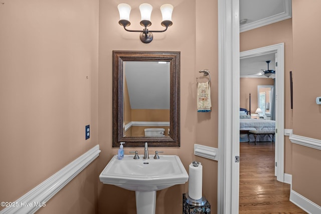 bathroom featuring baseboards, wood finished floors, a ceiling fan, and a sink