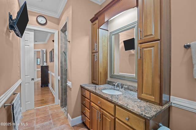 full bathroom featuring vanity, baseboards, a tile shower, ornamental molding, and tile patterned floors