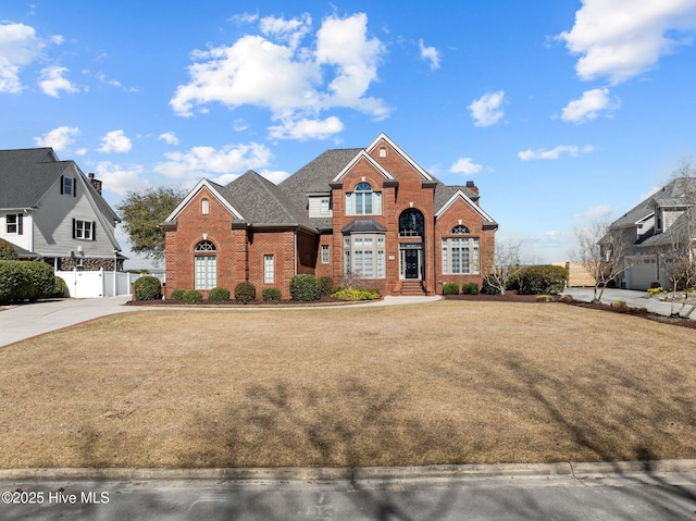 view of front of house with driveway, a gate, a front lawn, fence, and brick siding