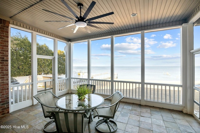 sunroom featuring wooden ceiling, a view of the beach, ceiling fan, and a water view