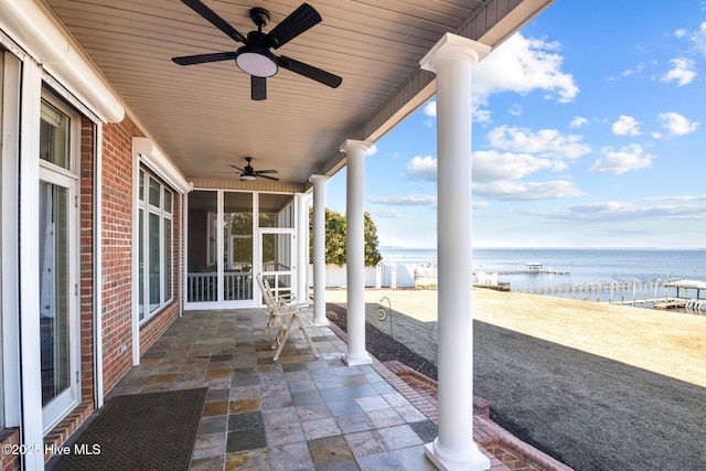 view of patio / terrace with a beach view, a ceiling fan, and a water view