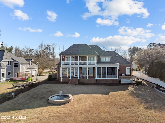 back of property featuring a balcony, fence, and a sunroom