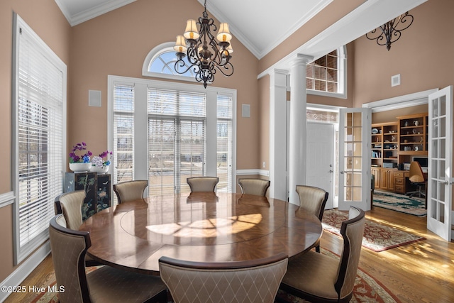 dining area with french doors, high vaulted ceiling, crown molding, and wood finished floors