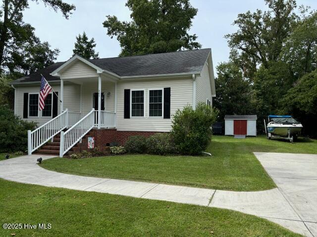 bungalow-style house featuring a front lawn, an outbuilding, and covered porch