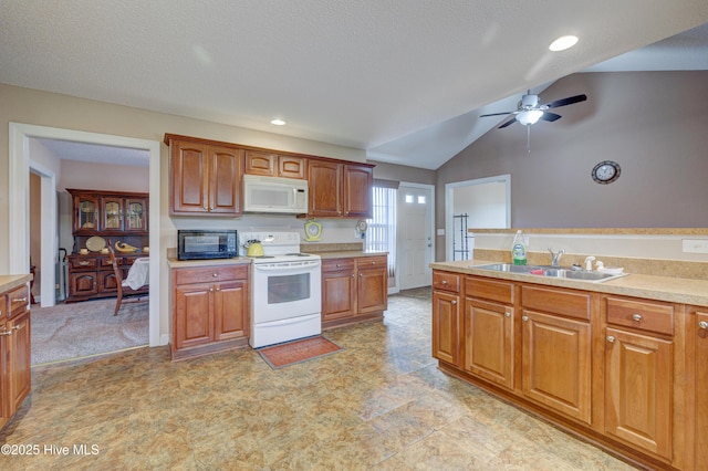 kitchen featuring light countertops, vaulted ceiling, brown cabinetry, white appliances, and a sink