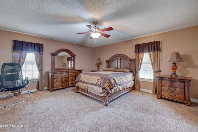 carpeted bedroom with baseboards, multiple windows, a textured ceiling, and ceiling fan