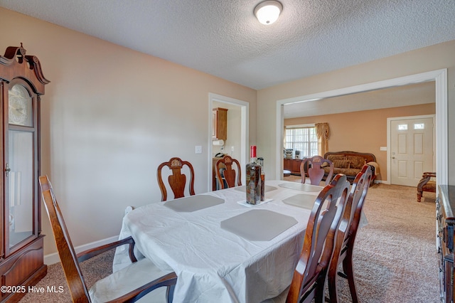 dining area featuring light colored carpet, baseboards, and a textured ceiling