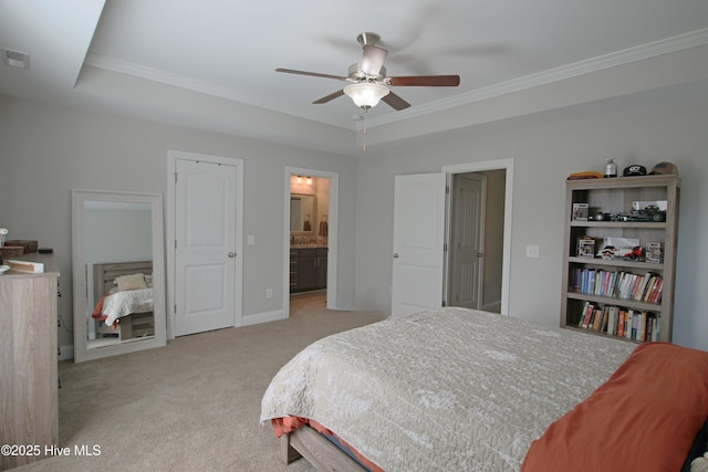 bedroom with visible vents, a tray ceiling, connected bathroom, crown molding, and light colored carpet