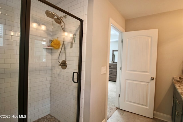 full bath with baseboards, a stall shower, vanity, and tile patterned flooring