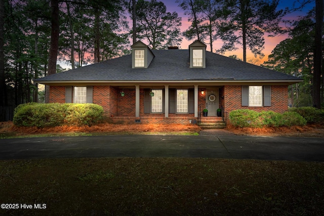 view of front of home with brick siding and roof with shingles