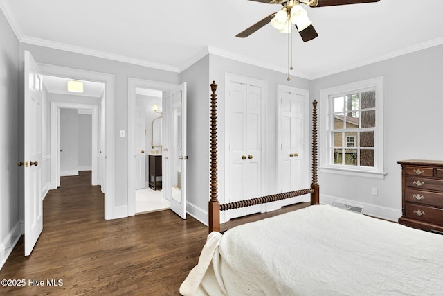 bedroom featuring dark wood-type flooring, crown molding, visible vents, and multiple closets