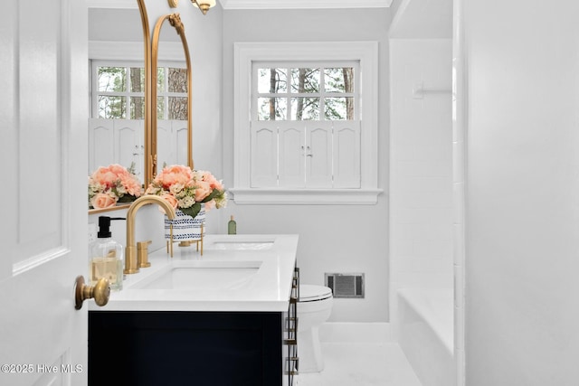 bathroom featuring visible vents, plenty of natural light, toilet, and vanity