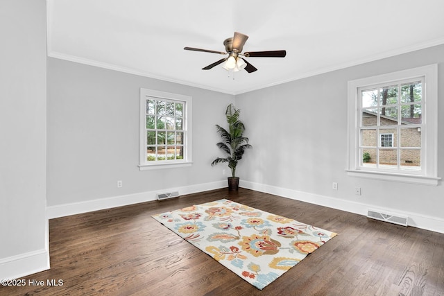 empty room featuring visible vents, wood finished floors, baseboards, and ornamental molding