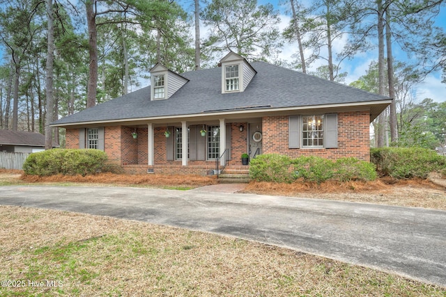 view of front facade with brick siding, crawl space, driveway, and a shingled roof